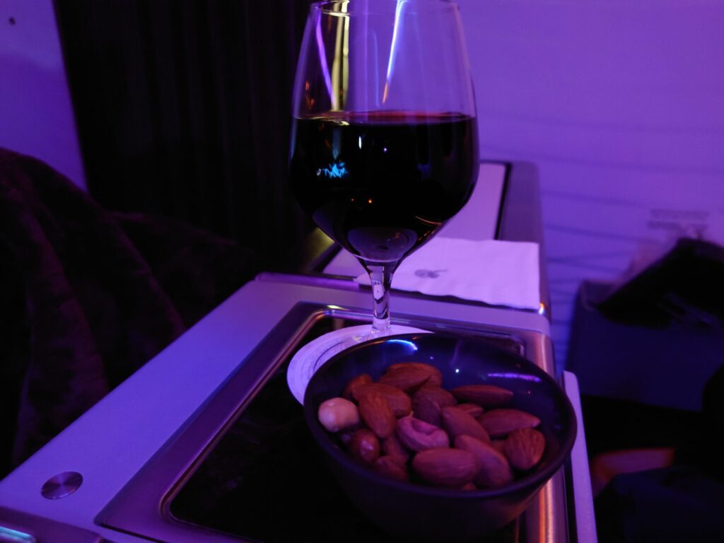 カタール航空ビジネスクラスのウエルカムドリンクの赤ワインと、おつまみのナッツ