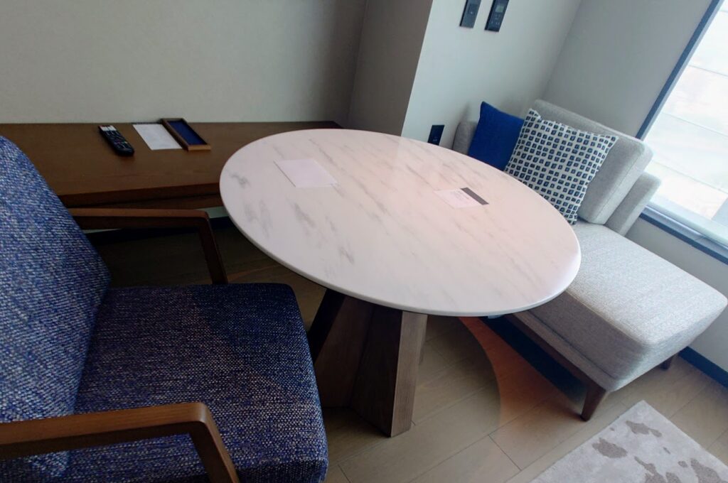 シェラトン鹿児島の部屋の窓際に、ソファ、テーブル、椅子がある