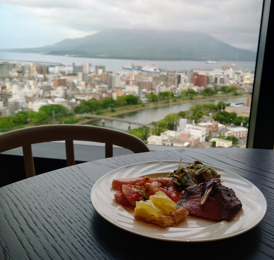 シェラトン鹿児島のクラブラウンジ　イブニングカクテルサービスの料理が、桜島が見える窓際のテーブルに置いてある