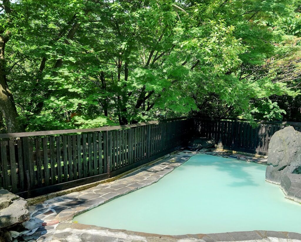 峡雲荘の大浴場　露天風呂は、木々の下や、岩の後ろに陰があり、日中も日焼けを気にせずに温泉浴が楽しめる