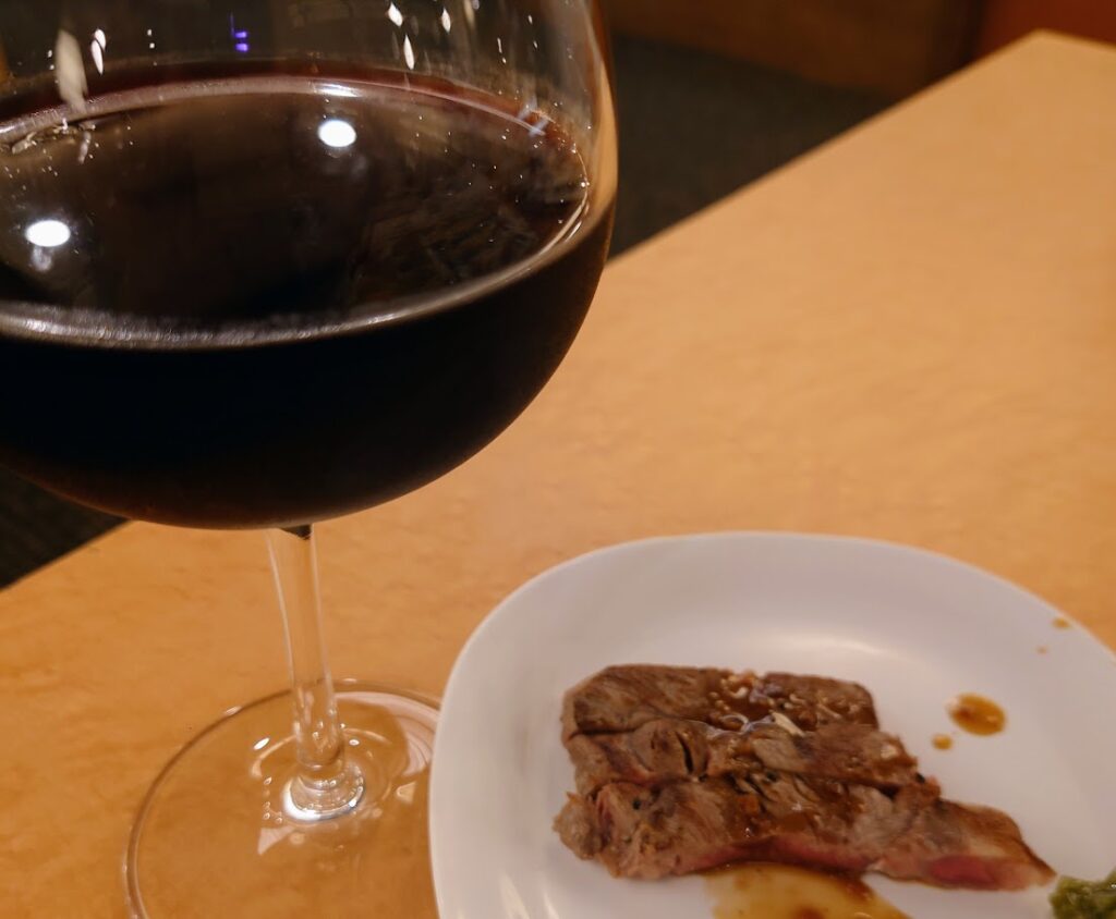 水上温泉「松乃井」の夕食ビュッフェ　グラスワインとステーキがテーブルにのっている