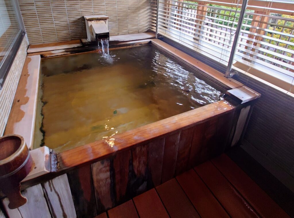 水上温泉「松乃井」露天風呂付客室　露天風呂では、源泉が湯船からあふれ出している
