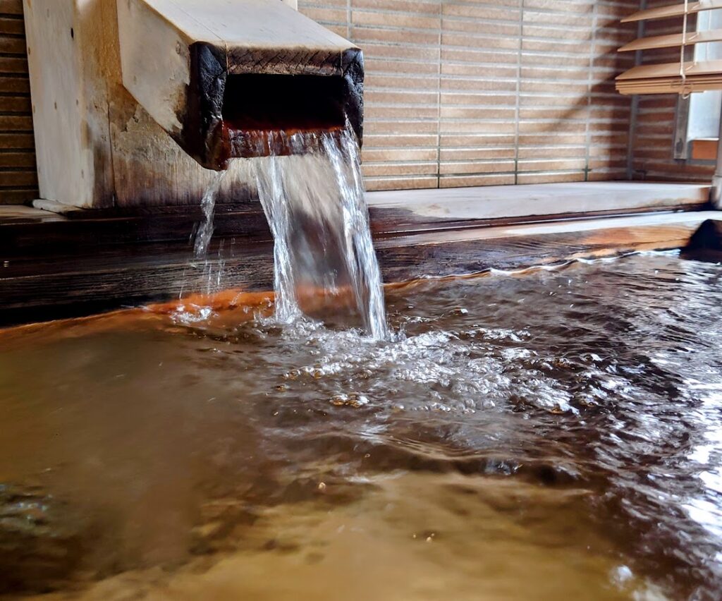 水上温泉「松乃井」露天風呂付客室　源泉が湯船に勢いよくあふれこんでいる様子