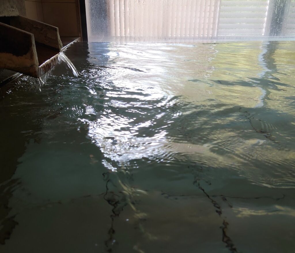 水上温泉「松乃井」の大浴場「月あかりの湯」の内湯には、源泉が勢いよく流れ込んでいる