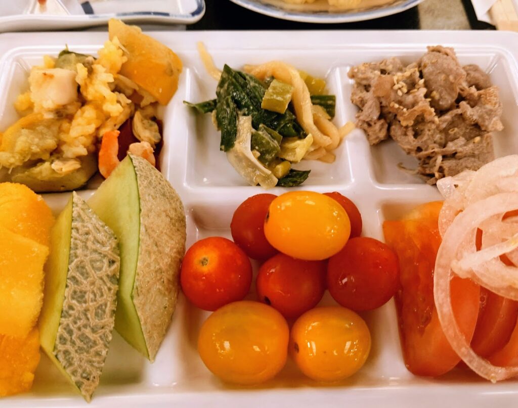 水上温泉「松乃井」の夕食ビュッフェ　皿にはトマト、メロン、しゃぶしゃぶなどがのっている