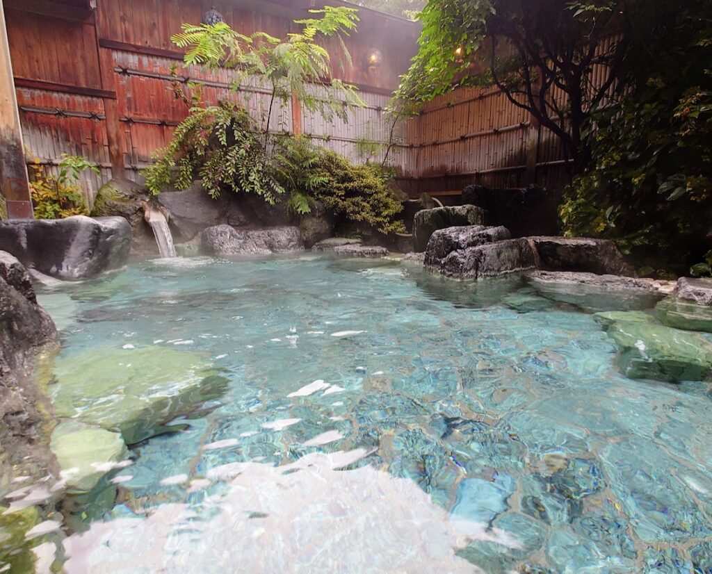 水上温泉「松乃井」の大露天風呂「火あかりの湯」　岩と木で囲まれた情緒ある湯船