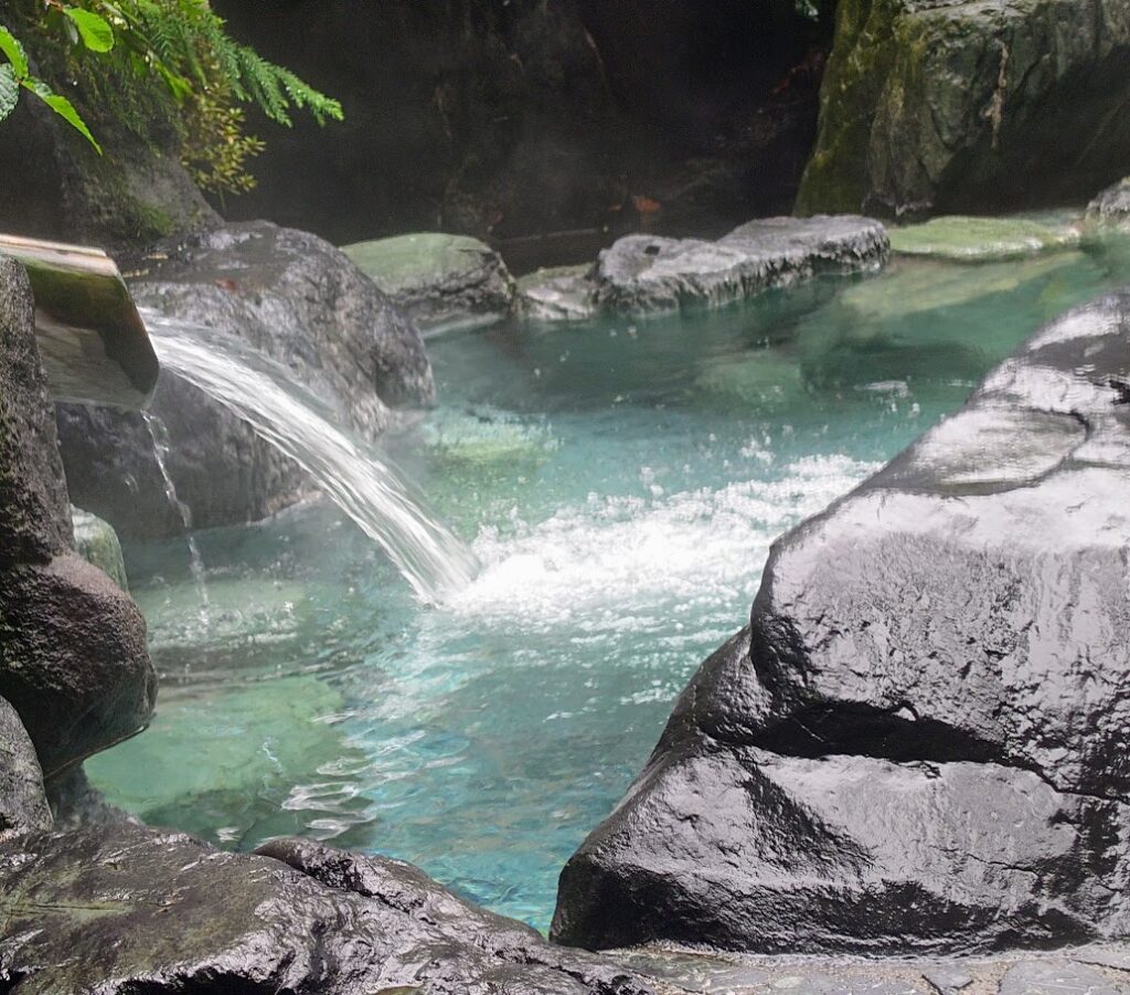 水上温泉「松乃井」の大露天風呂「火あかりの湯」　岩づくりの露天には、温泉が勢いよく流れこんでいる